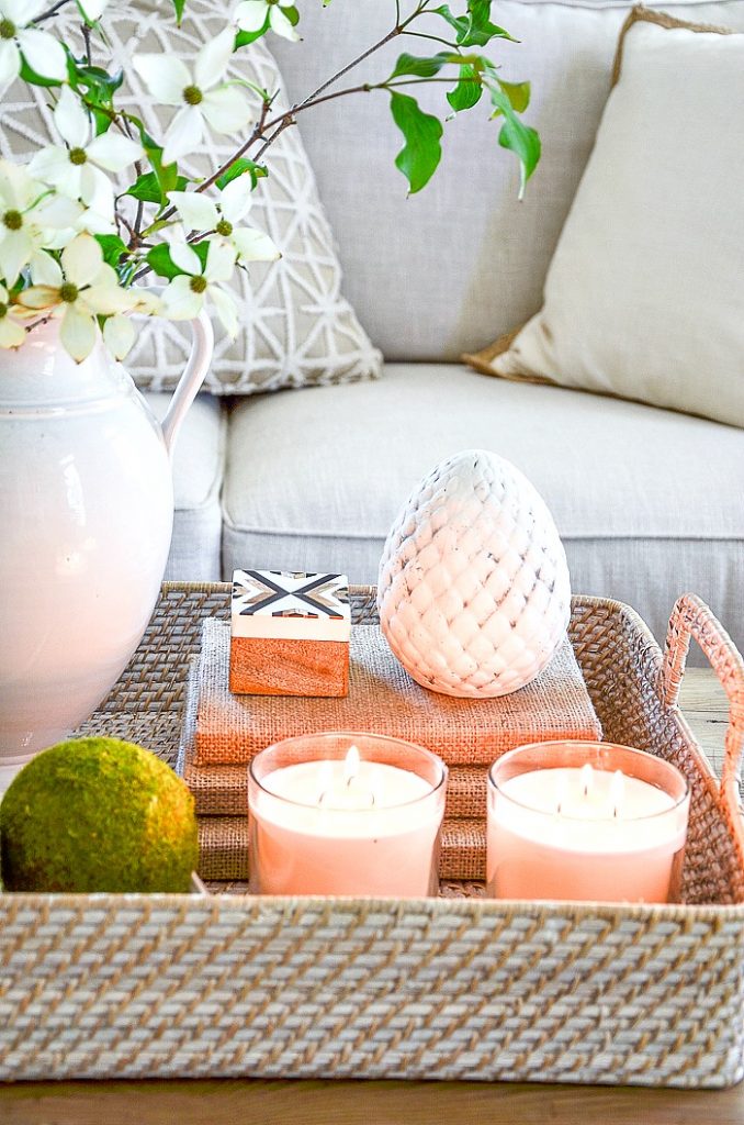  TWO CANDLES in glass candleholders are COFFEE TABLE ACCESSORIES in a basket on a table 
